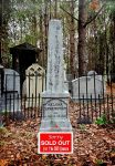 White stone memorial in a forest cemetery with ‘Sorry Sold Out’ sign.