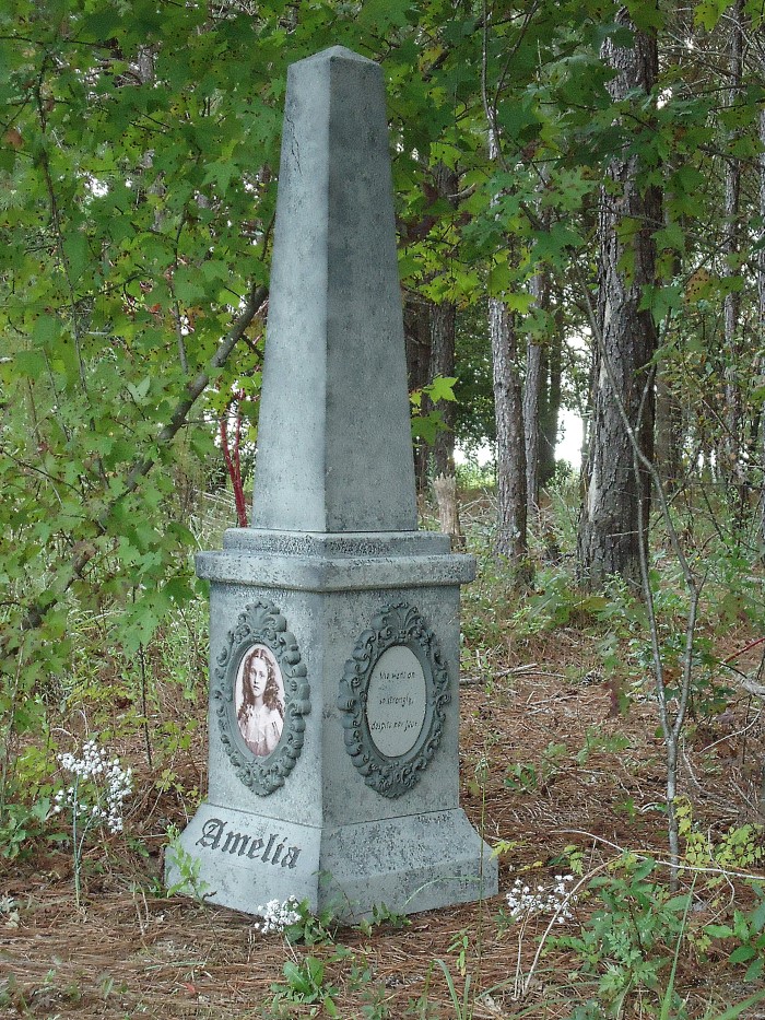 A weathered stone obelisk monument in a wooded area. A weathered stone obelisk monument in a wooded area.