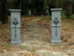 Two stone pillars with lion head water spouts in a wooded area.