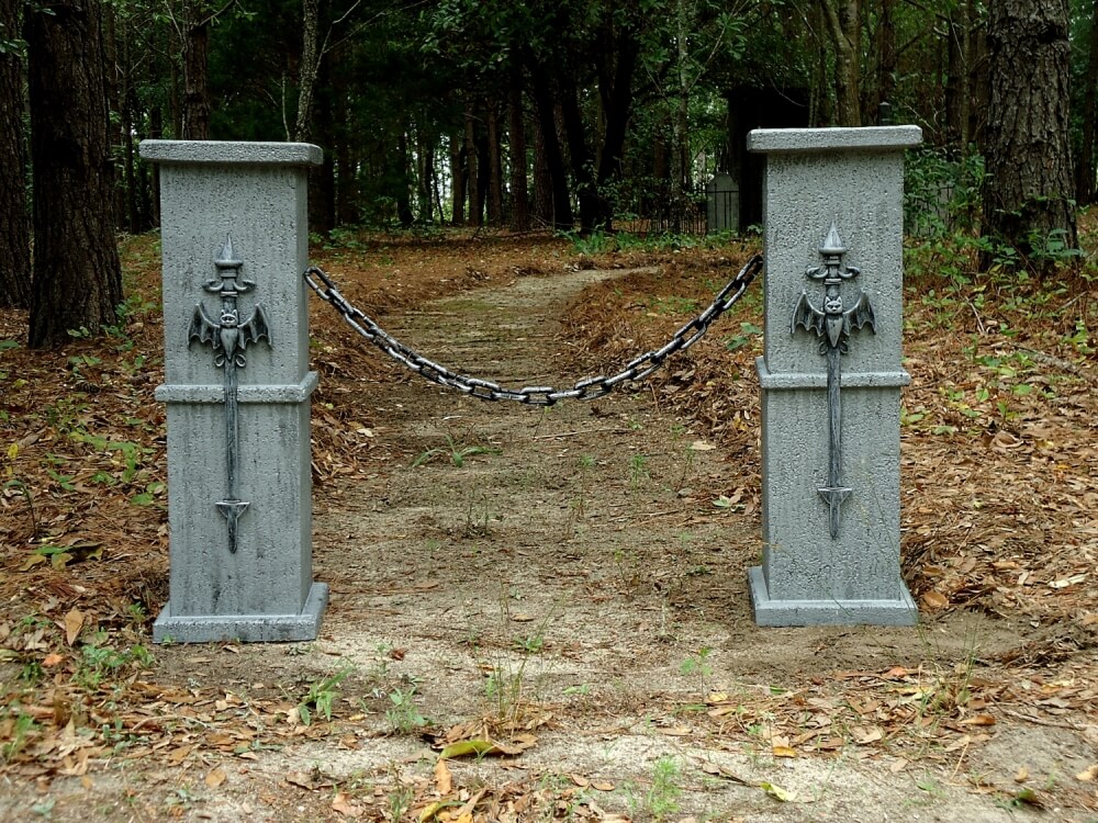 Two concrete pillars with chains block a forest path. Two concrete pillars with chains block a forest path.