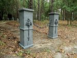 Two stone pillars with lion head water spouts in a wooded area.