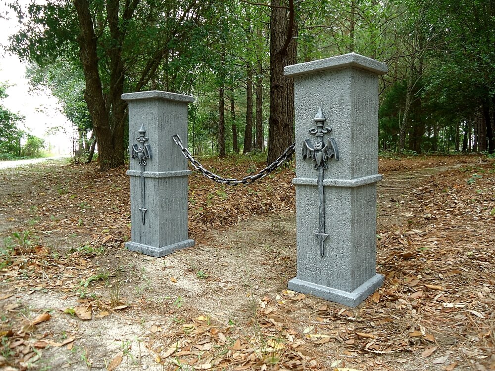Two gray stone pillars in a wooded area. Two gray stone pillars in a wooded area.