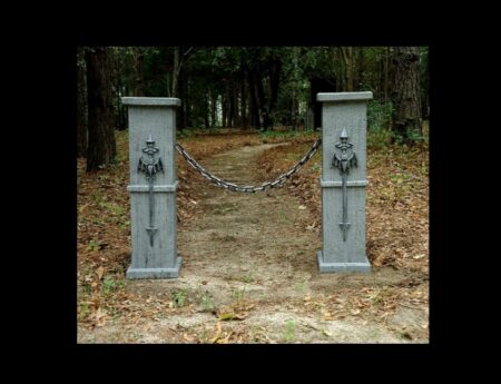 Two stone pillars with lion head water spouts in a wooded area.