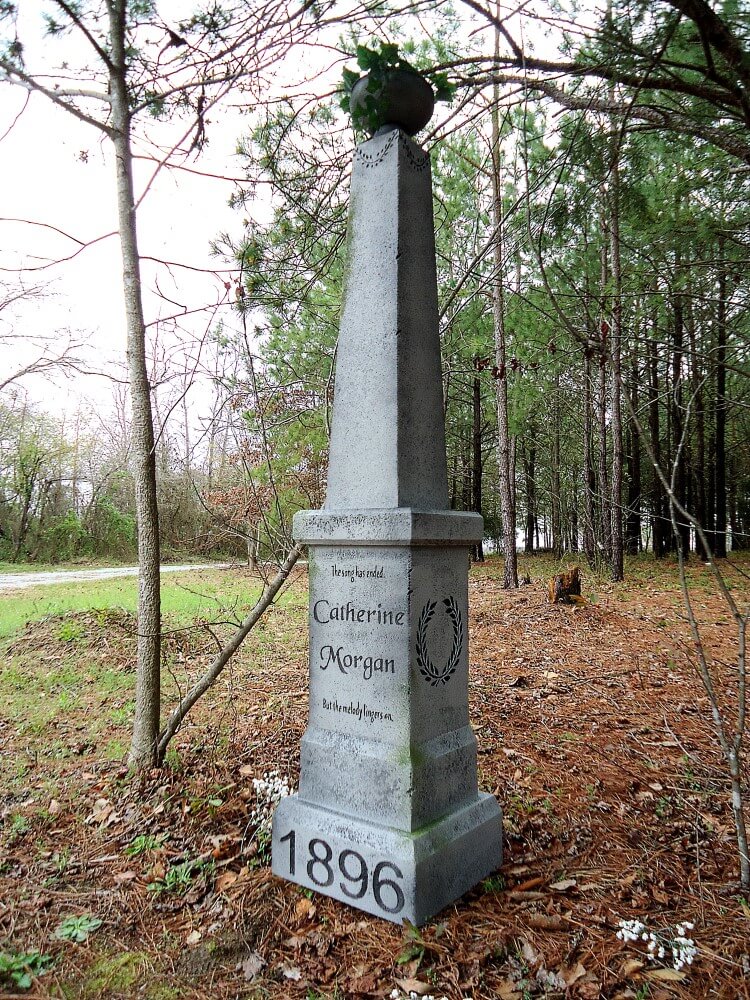 Tall stone monument in a wooded area with engraved text and date. Tall stone monument in a wooded area with engraved text and date.