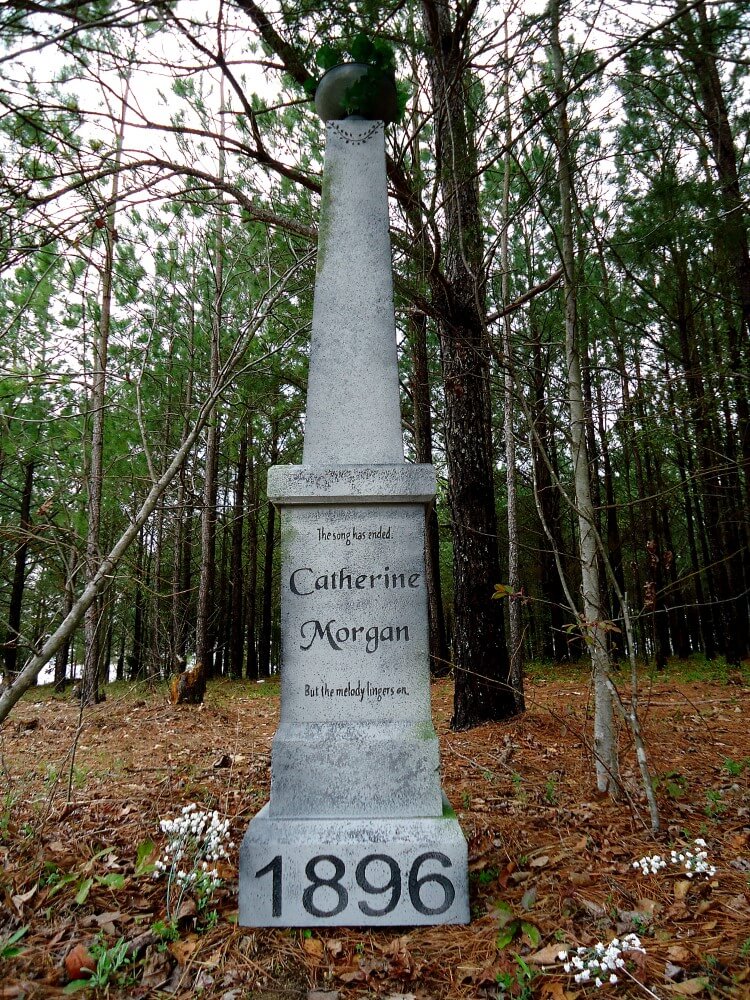 A tall white monument in a wooded area dated 1896. A tall white monument in a wooded area dated 1896.