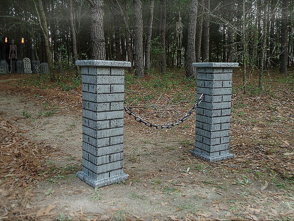 Two stone pillars with chains between them at a forest entrance. Two stone pillars with chains between them at a forest entrance.
