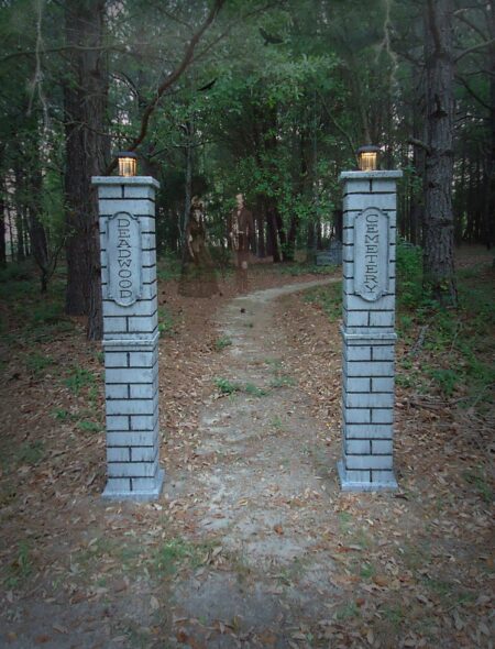 Two brick pillars stand at a forest path entrance.