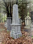 White stone memorial in a forest cemetery with ‘Sorry Sold Out’ sign.