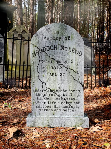 Gravestone of a Revolutionary War soldier in a wooded cemetery.