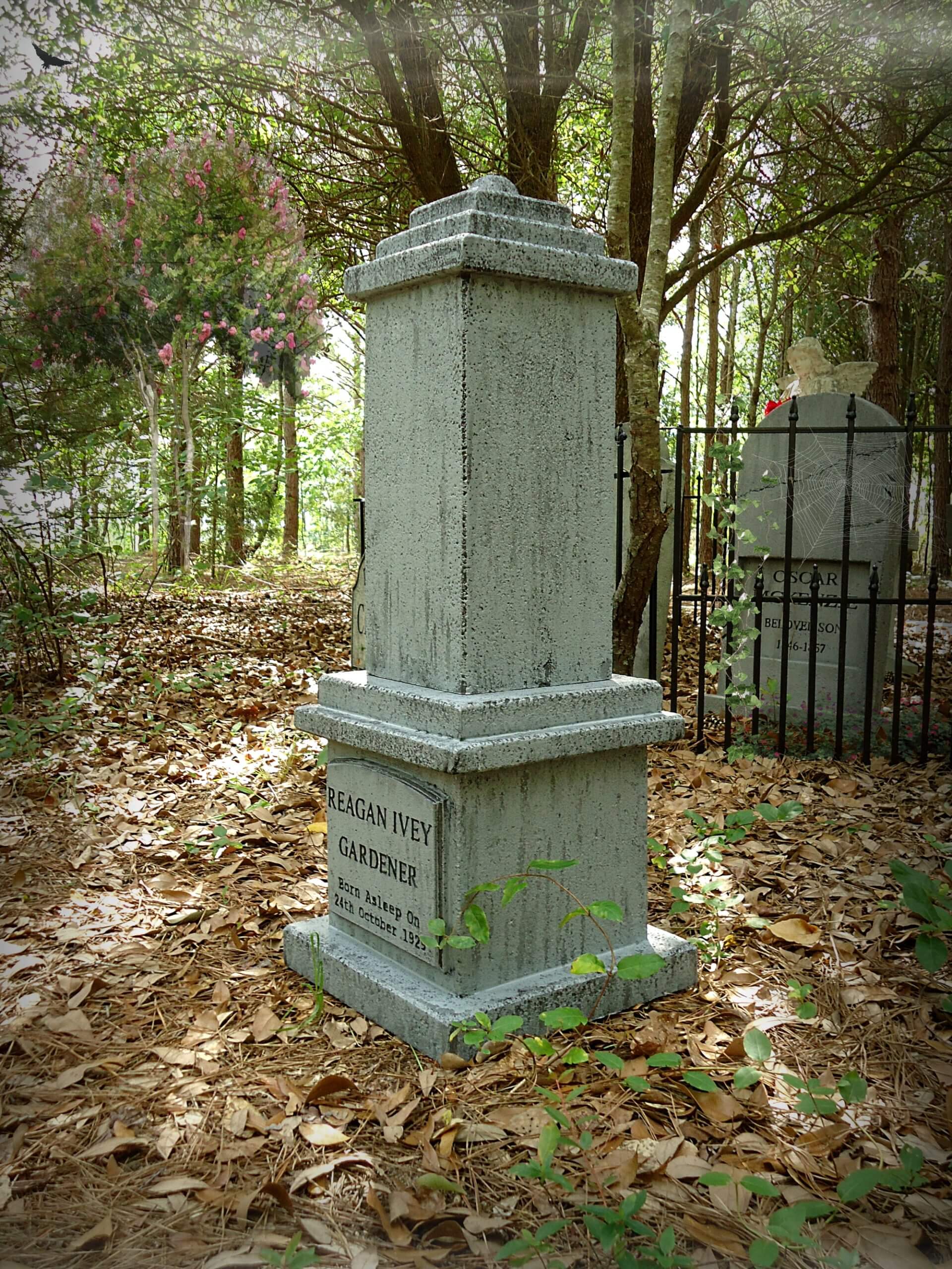 A weathered stone monument in a wooded cemetery area. A weathered stone monument in a wooded cemetery area.
