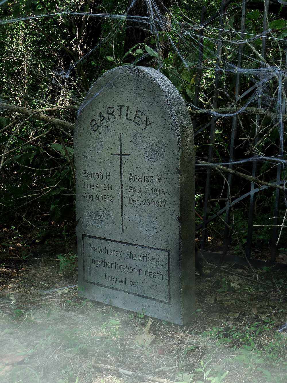 Old weathered gravestone in a wooded area with inscriptions and a cross. Old weathered gravestone in a wooded area with inscriptions and a cross.