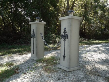 Two stone pillars with metal crosses in a wooded area.