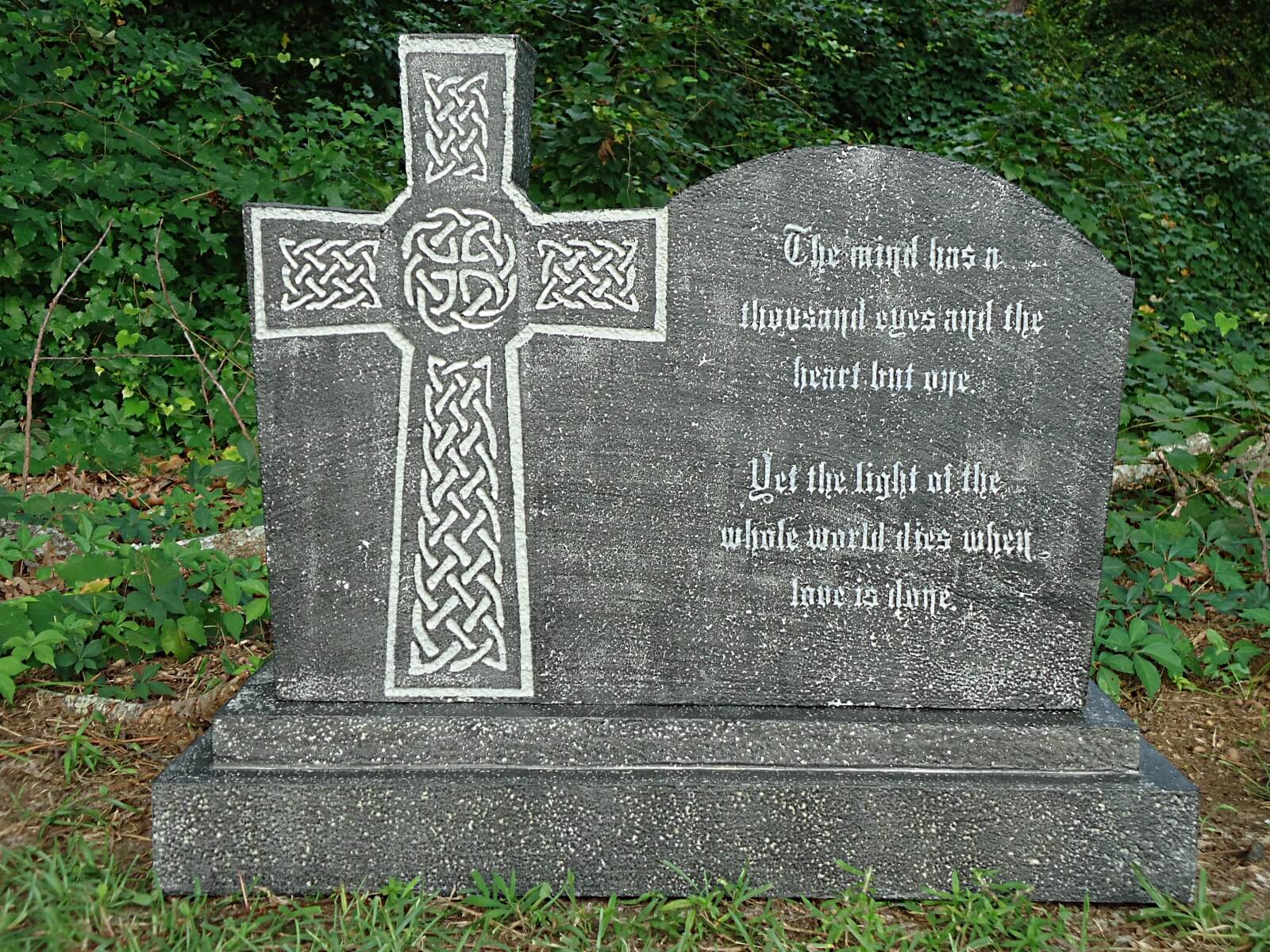 A stone Celtic cross gravestone in a grassy area. A stone Celtic cross gravestone in a grassy area.