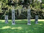 Four decorative stone pillars with intricate designs stand on a grassy lawn.