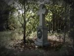 Eerie stone cross monument with a haunting face in the forest, marked as sold out.