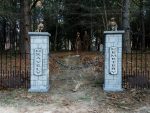 Two stone pillars at a forest entrance with a pathway beyond.