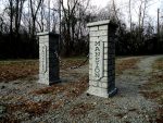 A sold-out sign on a pathway flanked by two white pillars in a forested area.