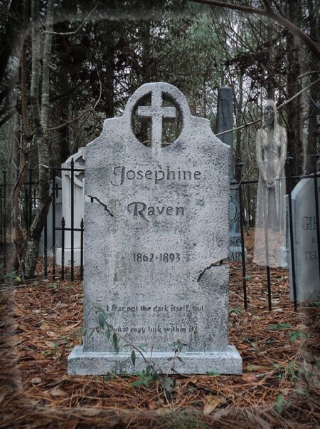 A weathered tombstone in a wooded cemetery.