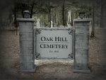 Entrance sign of Oak Hill Cemetery surrounded by trees.