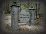 Entrance sign of Oak Hill Cemetery surrounded by trees.