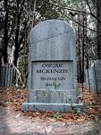 Gravestone of Oszune McKenzie in a wooded graveyard.