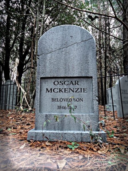 Gravestone of Oszune McKenzie in a wooded graveyard.