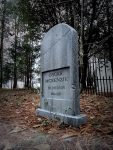Gravestone of Oszune McKenzie in a wooded graveyard.